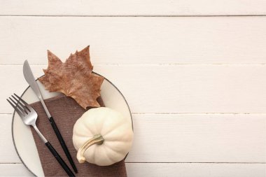 Beyaz ahşap zemin üzerinde balkabağı ve kurumuş yaprak ile sonbahar masa ayarı