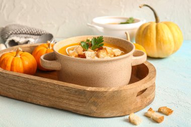 Ekmek arası balkabağı kremalı çorba ve açık mavi arka planda maydanoz.