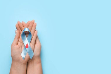 Mavi arka planda farkındalık kurdelesi ve kağıt kan damlası olan bir kadın. Diyabet kavramı