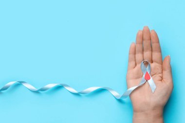 Mavi arka planda farkındalık kurdelesi ve kağıt kan damlası olan bir kadın. Diyabet kavramı
