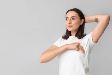 Genç kadın göğüslerini ışık arka plan üzerinde kontrol. Kanser farkındalık kavramı