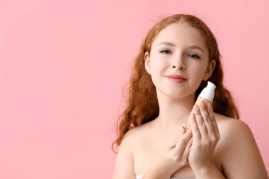 Pembe arka planda makyaj vakfı olan genç kızıl saçlı kadın, yakın plan.