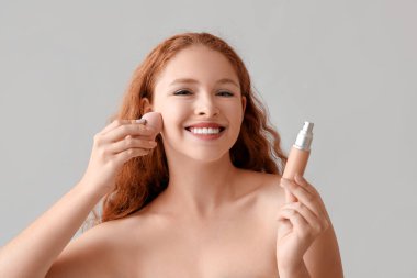 Makyaj temeli açık arkaplanda genç kızıl saçlı kadın.