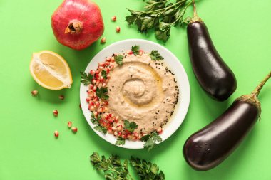 Lezzetli baba ghanoush tabağı ve yeşil arka plandaki malzemeler.