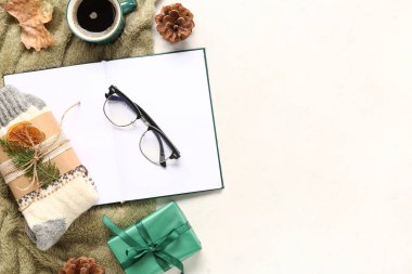 Sıcak çoraplar, bir fincan kahve ve beyaz arka plan üzerine boş bir kitapla güzel bir kompozisyon.