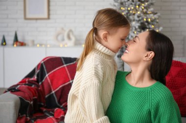 Genç bir anne ve küçük kızı Noel arifesinde evlerinde burunlarına dokunuyorlar.