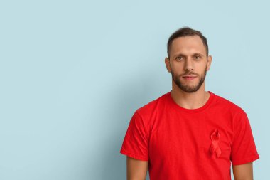 Mavi arka planda kırmızı kurdeleli genç adam. AID farkındalık kavramı