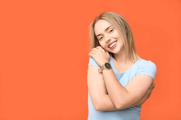 Young woman hugging herself on orange background