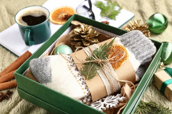 Box with warm socks and Christmas decor on table