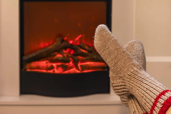 Woman in warm socks near fireplace at home on Christmas eve