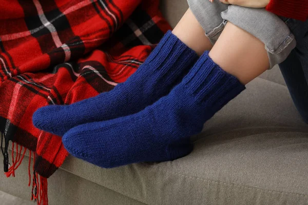 Woman in blue knitted socks sitting on sofa at home