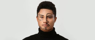 Işıklı arka planda yüzü boyanmış genç bir Afro-Amerikalı.