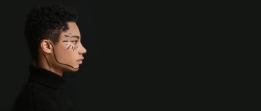 Siyah arka planda yüzü boyalı, mesaj için yeri olan genç Afro-Amerikalı bir adam.