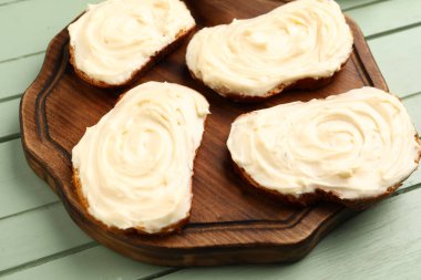 Tahta tahtada yeşil ahşap arka planda krem peynirli lezzetli sandviçler.