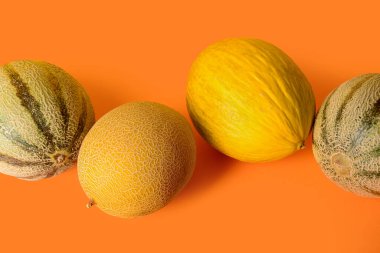 Turuncu arka planda farklı tatlı kavunlar