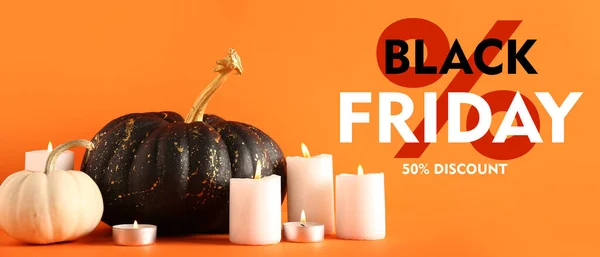Painted pumpkins, candles and text BLACK FRIDAY on orange background