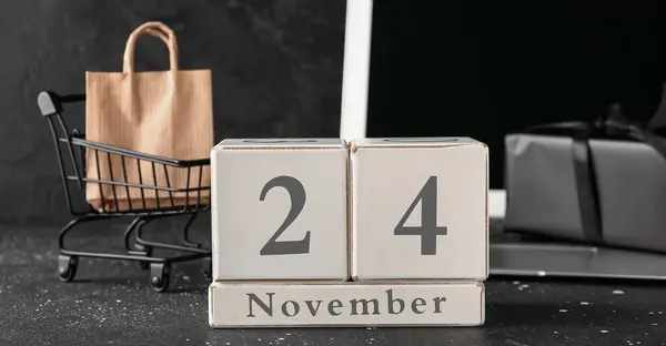 日付が付いているキューブ カレンダー 暗い背景のショッピング カートそしてラップトップ ブラックフライデーセール — ストック写真
