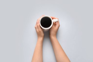 Beyaz arka planda bir fincan sıcak kahve tutan kadın.
