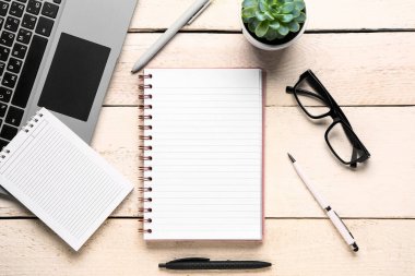 Beyaz ahşap arka planda gözlüklü ve dizüstü bilgisayarlı defter