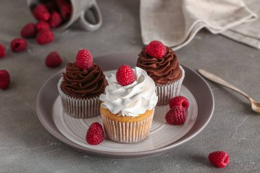 Gri arkaplanda ahududu olan bir tabak lezzetli kek.