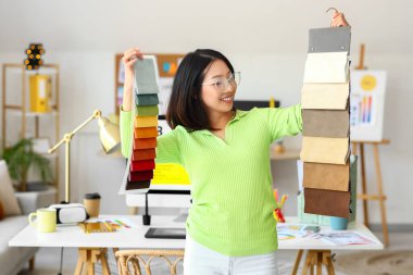 Ofisinde kumaş örnekleri olan Asyalı iç mimar.