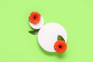 Alçı podyumlu kompozisyon ve yeşil arka planda güzel kırmızı gerbera çiçekleri.