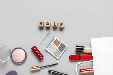 Makyaj malzemeli alışveriş çantası ve gri arka planda metin satışı