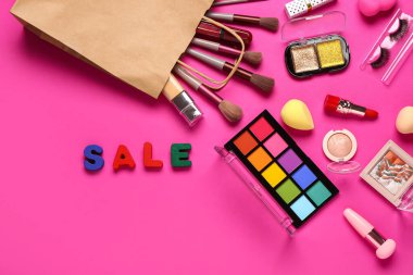 Makyaj malzemeli alışveriş çantası ve pembe arka planda metin satışı