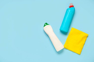 Deterjan şişeleri ve mavi arka planda sarı bez.