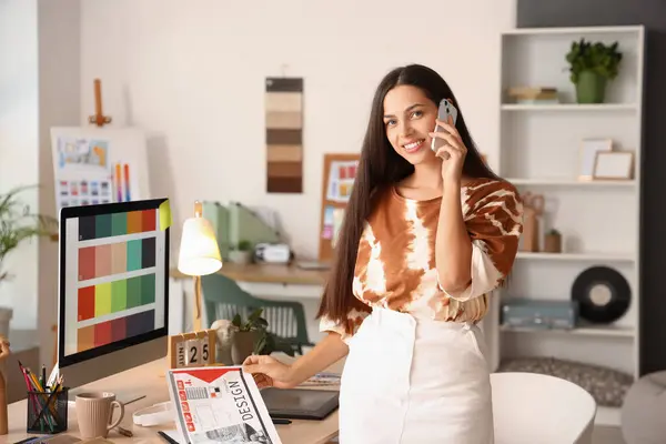 Female interior designer talking by mobile phone in office