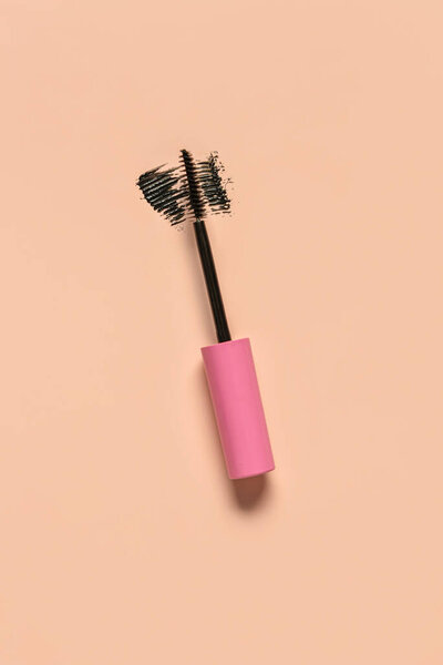 Black mascara brush with sample on pink background
