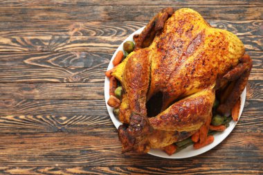 Ahşap zemin üzerinde Şükran Günü için lezzetli kızarmış hindi ve farklı sebzelerle dolu bir tabak.