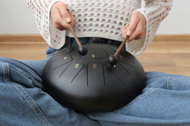 Elinde sopalarla evde glukofon çalan güzel genç bir kadın.