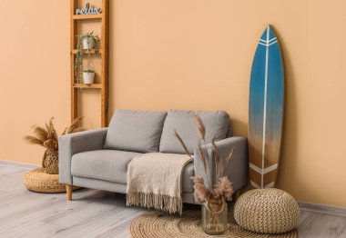 Sörf tahtası, raf ünitesi ve kanepesi olan modern şık bir oda.