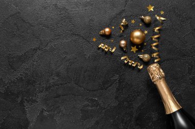 Siyah arka planda yeni yıl partisi için bir şişe şampanya ve dekorasyonla harika bir kompozisyon.