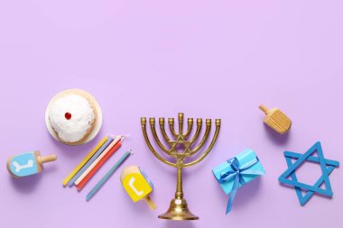 Menorah, dreidels, hediye kutusu ve leylak arkaplanlı donut içeren Hannukah kompozisyonu