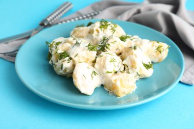 Bir tabak lezzetli patates salatası. Mavi arka planda yeşiller, yakın plan.