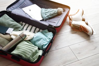 Kışlık giysiler ve aksesuarlarla dolu bavulu aç.