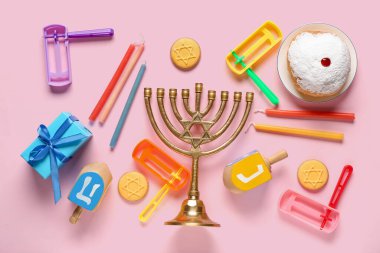 Menorah, donut, dreidels ve pembe arka planda çıngırak içeren Hannukah kompozisyonu