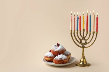 Bej arka planda Hanuka kutlaması için menorah ve lezzetli donutlar.