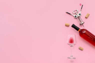 Pembe arka planda tirbuşonlu cam ve bir şişe nefis şarap.
