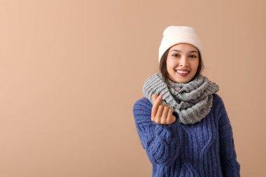 Kahverengi arka planda kalp hareketi gösteren sıcak eşarplı güzel bir Asyalı kadın.