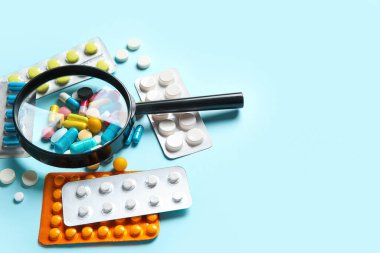 Mavi arka planda farklı haplar içeren büyüteç