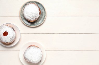 Beyaz ahşap arka planda Hanuka kutlaması için reçelli lezzetli çörekler.