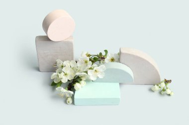 Gri arkaplanda dekoratif podyumlar ve çiçek açan şubeler