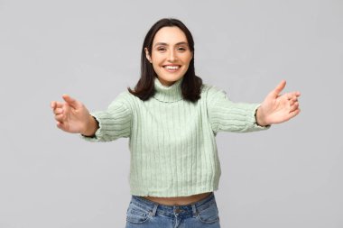 Genç bir kadın hafif arka planda sarılmak için kollarını açıyor.