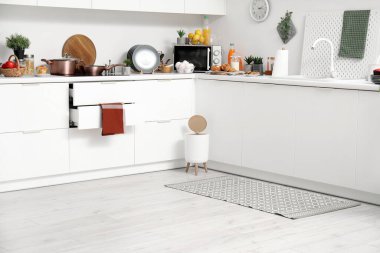 Modern mutfağın içinde şık halı, çöp kutusu ve beyaz tezgahlar var.