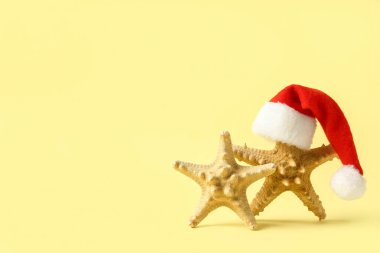Sarı arka planda Noel Baba şapkalı yıldız balıkları