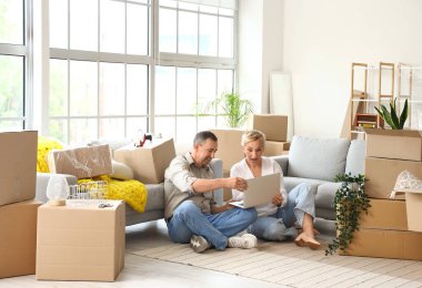 Taşınırken odada dizüstü bilgisayar kullanan yetişkin bir çift.