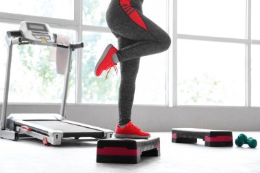 Spor salonunda adım atma egzersizi yapan bir kadın.